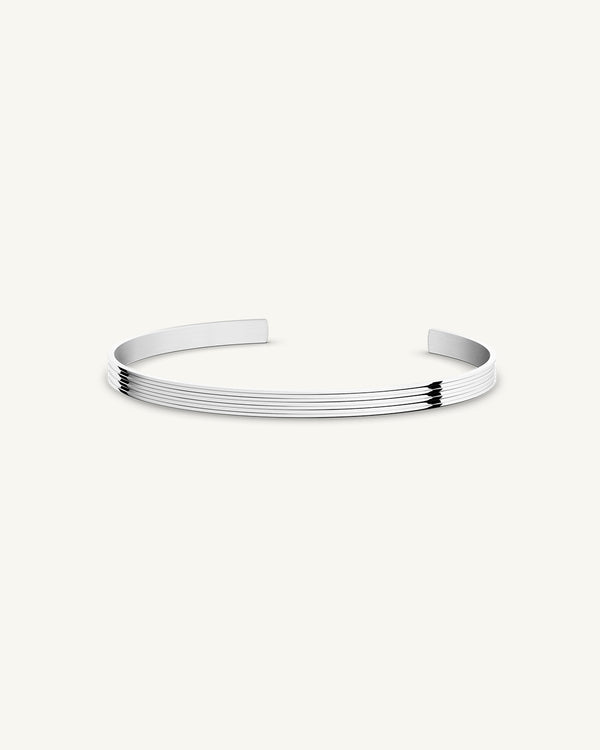 A polished stainless steel bangle in silver from Waldor & Co. One size. The model is Avant Bangle Polished