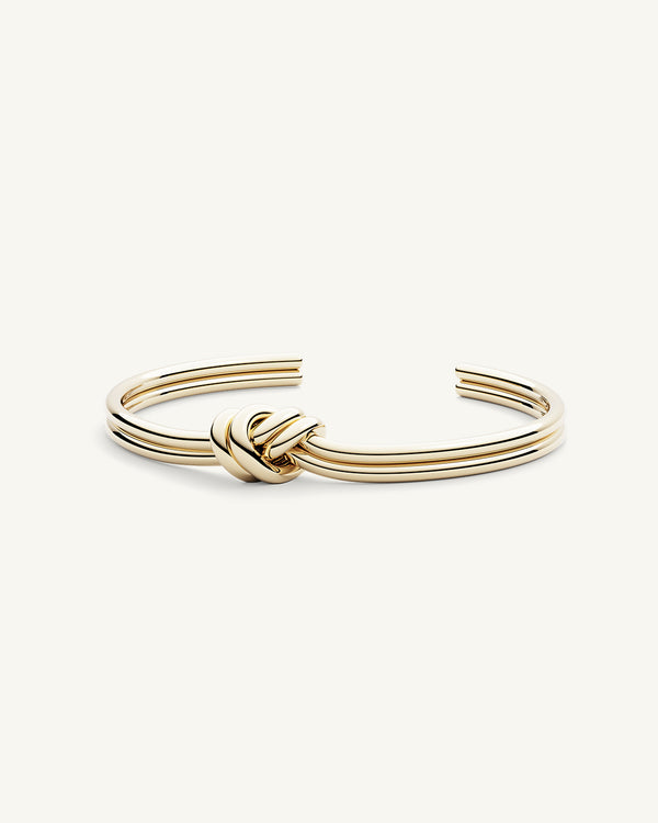 A Bangle in 14k-gold plated 316L stainless steel from Waldor & Co. One size. The model is Dual Knot Bangle Polished.