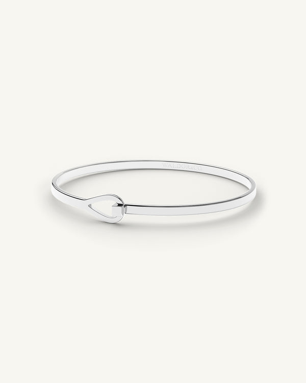 A polished stainless steel bangle in silver from Waldor & Co. The model is Signature Bangle Polished