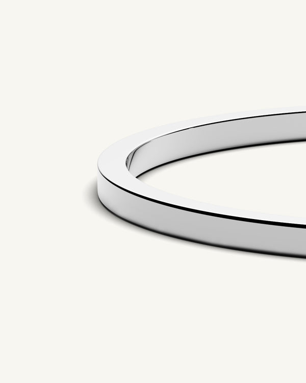 A polished stainless steel bangle in silver from Waldor & Co. One size. The model is Square Bangle Polished