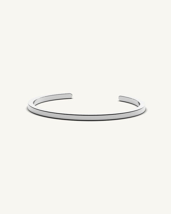 A polished stainless steel bangle in silver from Waldor & Co. One size. The model is Square Bangle Polished