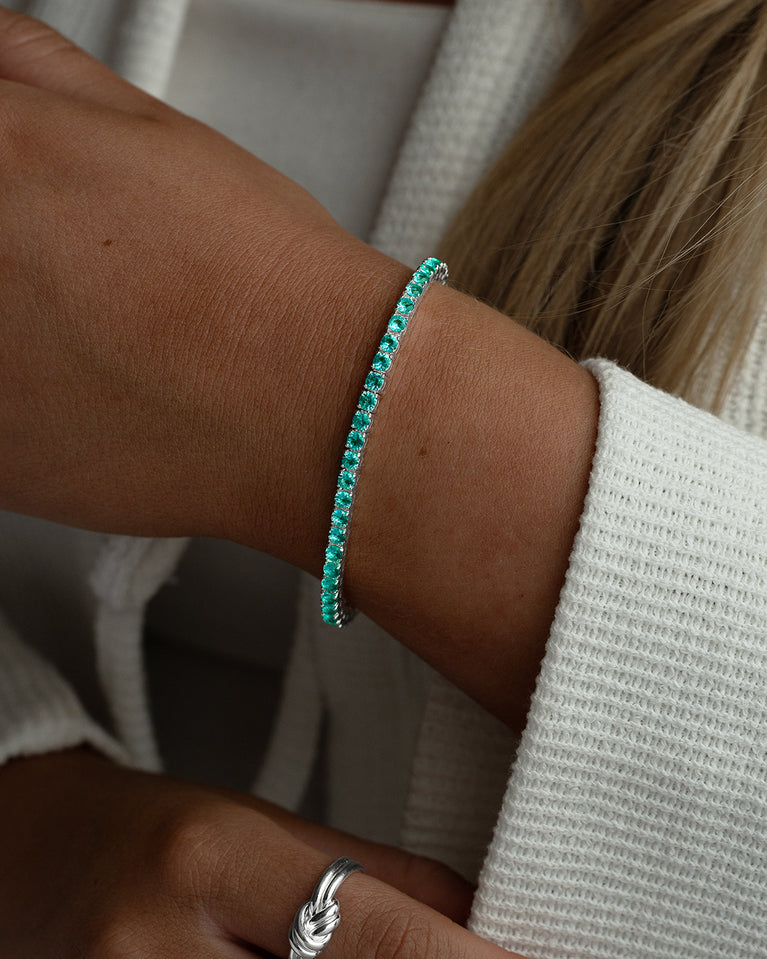 A polished stainless steel chain in silver with turquoise stones from Waldor & Co. The model is Tennis Chain Polished