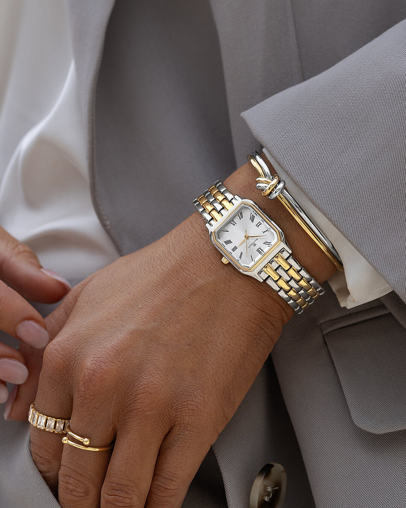 A square women’s watch and double knot bracelet in gold and silver from Waldor & co. The model is Eternal 22 Bellagio & Dual Knot Bangle.