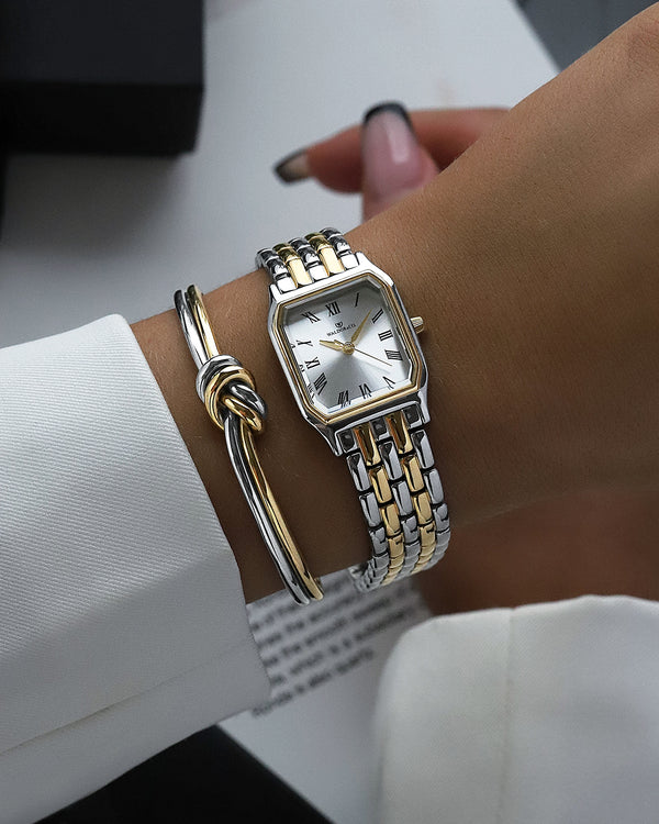 A square women’s watch and double knot bracelet in gold and silver from Waldor & co. The model is Eternal 22 Bellagio & Dual Knot Bangle.