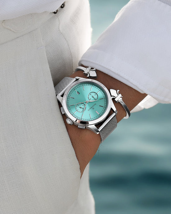 lifestyle_image. A round mens watch in rhodium-plated silver from Waldor & Co. with turquoise sunray dial and a second hand. Seiko movement. The model is Chrono 44 Sardinia 44mm.