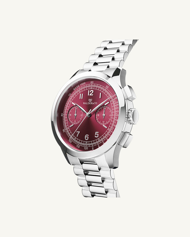 A round mens watch in rhodium-plated silver from Waldor & Co. with a burgundy colored sunray dial and a second hand. Seiko movement. The model is Chrono 39 Porto Cervo.