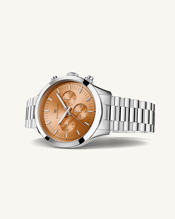 A round mens watch in rhodium-plated silver from Waldor & Co. with orange sunray dial and a second hand. Seiko movement. The model is Chrono 44 Como 44mm.