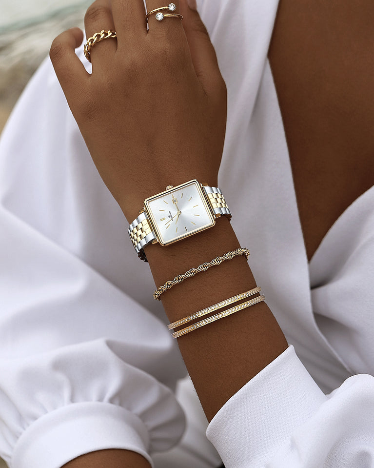  A square womens watch in silver and 14k gold from Waldor & Co. with silver sunray dial and a second hand. Seiko movement. The model is Delight 32 Chelsea 28x32mm.