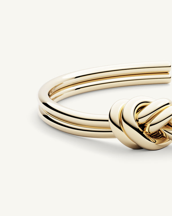 A Bangle in 14k-gold plated 316L stainless steel from Waldor & Co. One size. The model is Dual Knot Bangle Polished.