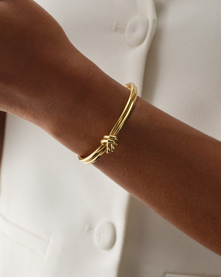 A Bangle in 14k-gold plated 316L stainless steel from Waldor & Co. One size. The model is Dual Knot Bangle Polished.