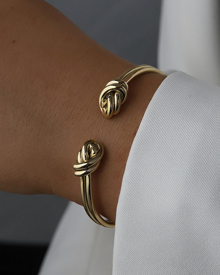 A Bangle in 14k-gold plated 316L stainless steel from Waldor & Co. One size. The model is Dual Knot Twin Bangle Polished.