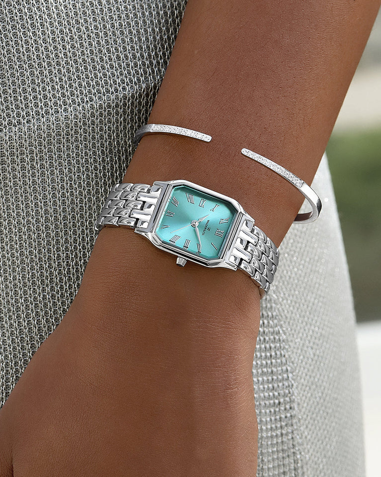 A square womens watch in Rhodium-plated 316L stainless steel from Waldor & Co. with turquoise Diamond Cut Sapphire Crystal glass dial. Seiko movement. The model is Eternal 22 Bellagio.