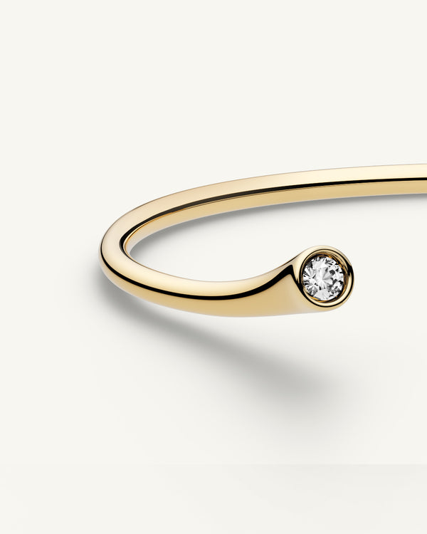 A polished stainless steel bangle in 14k gold from Waldor & Co. One size. The model is Delight Bangle.