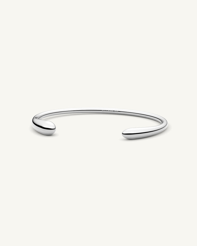 A Bangle in polished silver 316L stainless steel from Waldor & Co. One size. The model is Teardrop Bangle Polished.
