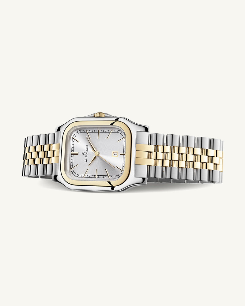 A square womens watch in silver and 14k gold from Waldor & Co. with silver sunray dial and a second hand. Seiko movement. The model is Delight 32 Chelsea 28x32mm.