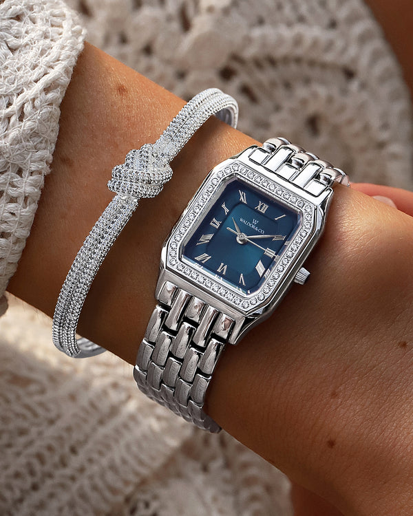  A square womens watch in Rhodium-plated 316L stainless steel from Waldor & Co. with dark blue dial. Bezel with premium crystals. Diamond Cut Sapphire Crystal glass dial. Seiko movement. The model is Eternal 22 Bellagio Pavè.