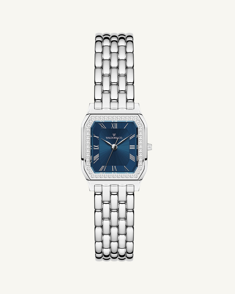 A square womens watch in Rhodium-plated 316L stainless steel from Waldor & Co. with dark blue dial. Bezel with premium crystals. Diamond Cut Sapphire Crystal glass dial. Seiko movement. The model is Eternal 22 Bellagio Pavè.