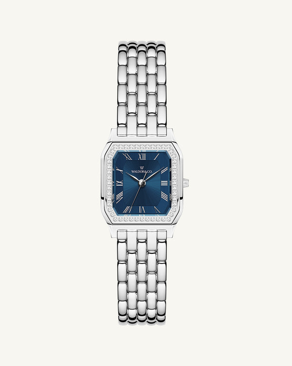A square womens watch in Rhodium-plated 316L stainless steel from Waldor & Co. with dark blue dial. Bezel with premium crystals. Diamond Cut Sapphire Crystal glass dial. Seiko movement. The model is Eternal 22 Bellagio Pavè.