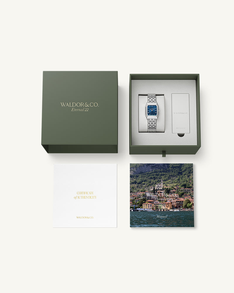 A square womens watch in Rhodium-plated 316L stainless steel from Waldor & Co. with dark blue dial. Bezel with premium crystals. Diamond Cut Sapphire Crystal glass dial. Seiko movement. The model is Eternal 22 Bellagio Pavè.