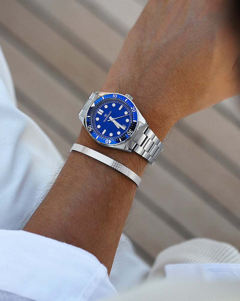 A round mens watch in Rhodium-plated 316L stainless steel from Waldor & Co. with Blue dial in brass with a rotating bezel. Applied indices, luminous hands. Ronda 715. The model is Novel 40 Cap d’Ail 40mm.